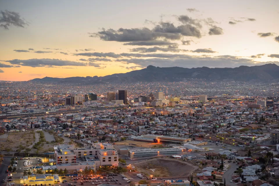 Aerial view of El Paso, Texas at dusk with mountains in background.